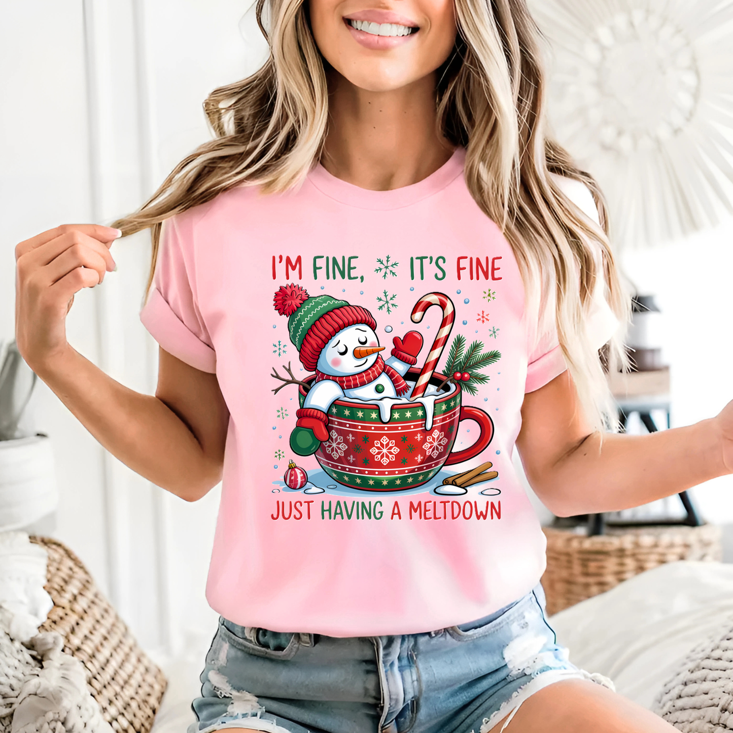 Woman in light pink Christmas shirt with “I’m Fine It’s Fine” snowman print.