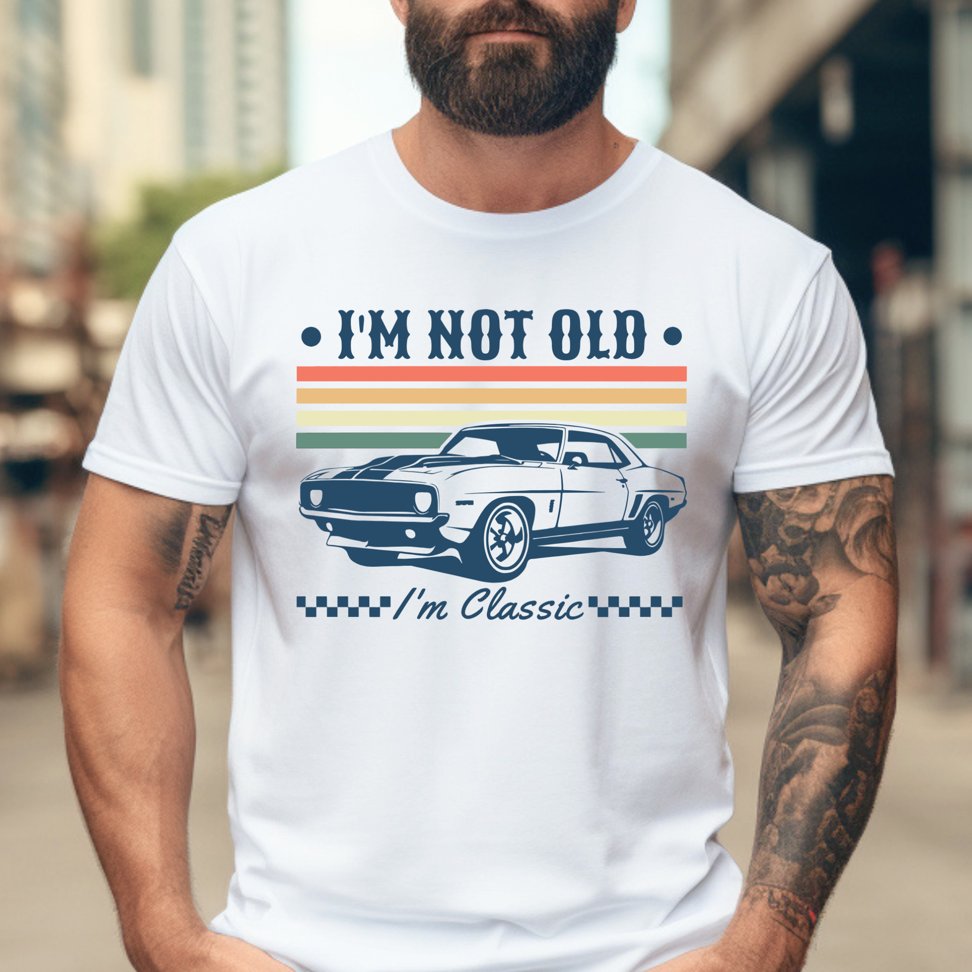 Man wearing a white t-shirt with a graphic and text 'I'm not old, I'm classic' on a blurred city street background.