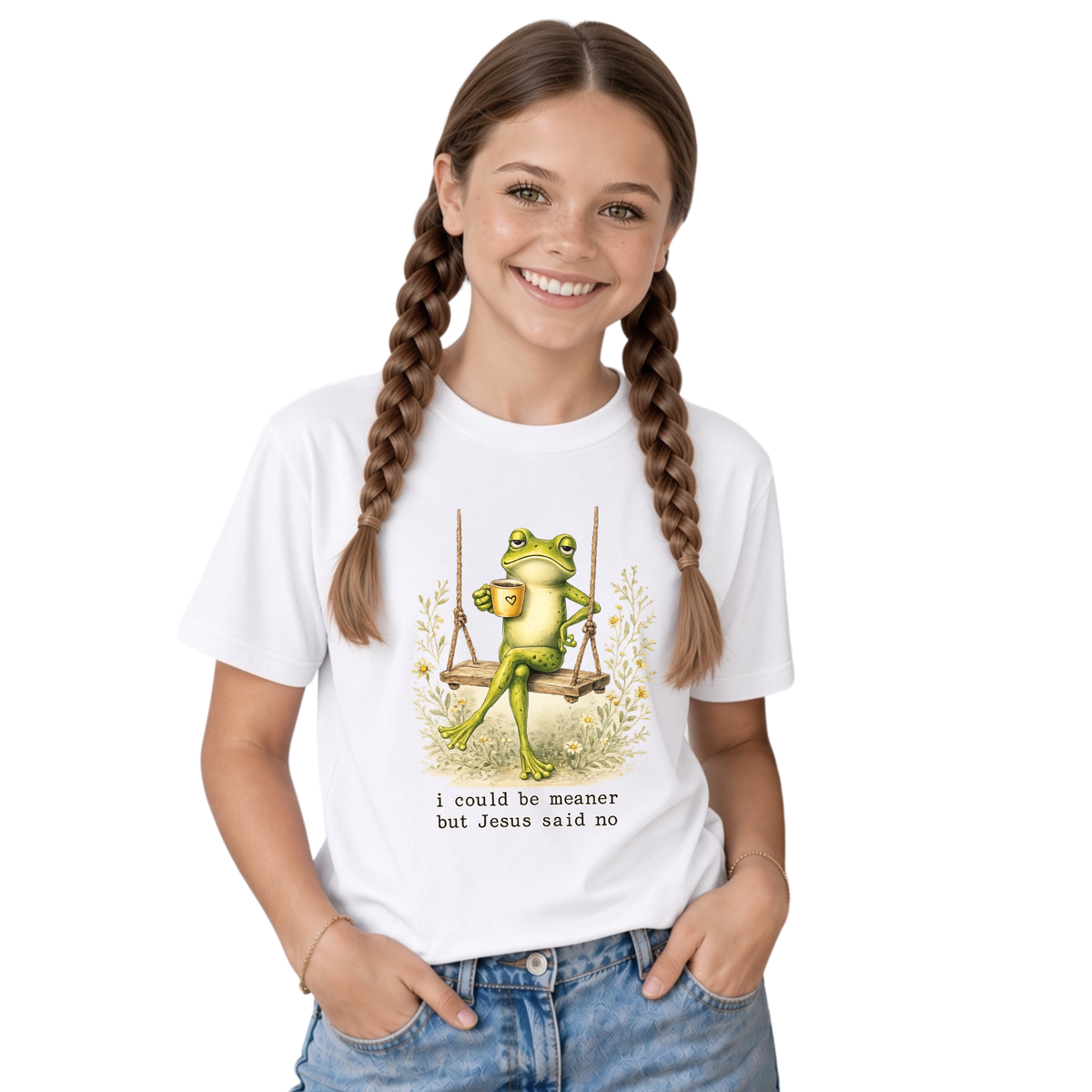 Youth girl wearing a white T-shirt with the I Could Be Meaner But Jesus Said No frog-on-a-swing Christian graphic.