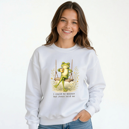 Young girl wearing a white crewneck sweatshirt with the I Could Be Meaner But Jesus Said No frog-on-a-swing Christian design.