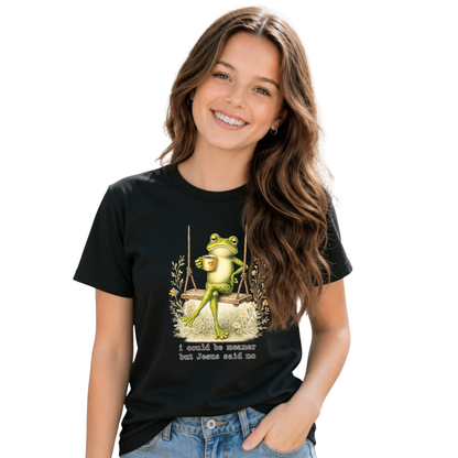 Young girl  wearing a black T-shirt with the I Could Be Meaner But Jesus Said No frog-on-a-swing faith graphic.