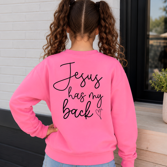 Back view of a girl wearing a Bright Pink youth sweatshirt with Jesus Has My Back script lettering and a heart cross graphic.