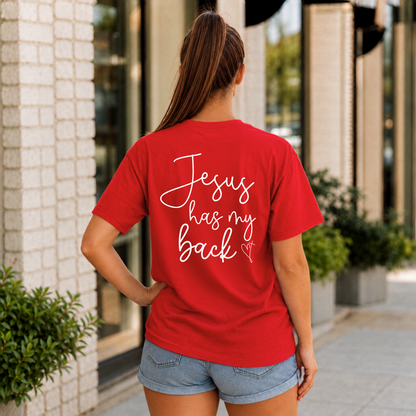 Back view of a woman wearing a red Jesus Has My Back T-shirt with white script lettering and a heart cross graphic.