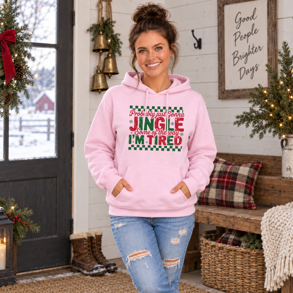 Woman wearing a light pink hoodie with red and green Probably Just Gonna Jingle Some of the Way I'm Tired Christmas design in a festive entryway