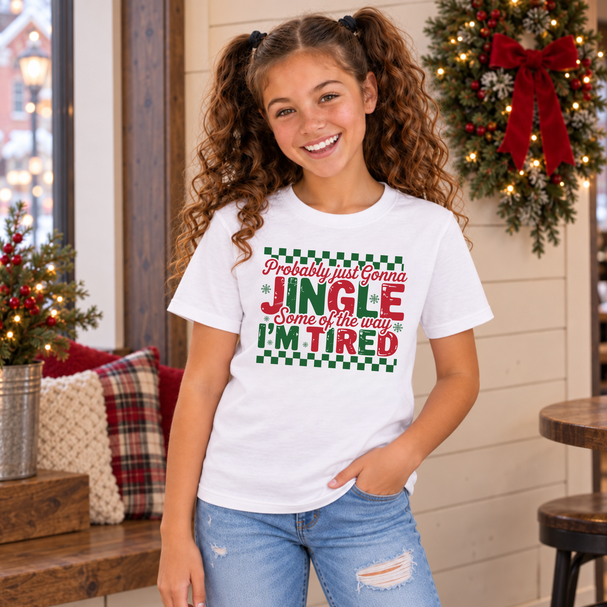 Girl wearing a white youth T-shirt with red and green Probably Just Gonna Jingle Some of the Way I'm Tired Christmas design in a festive room