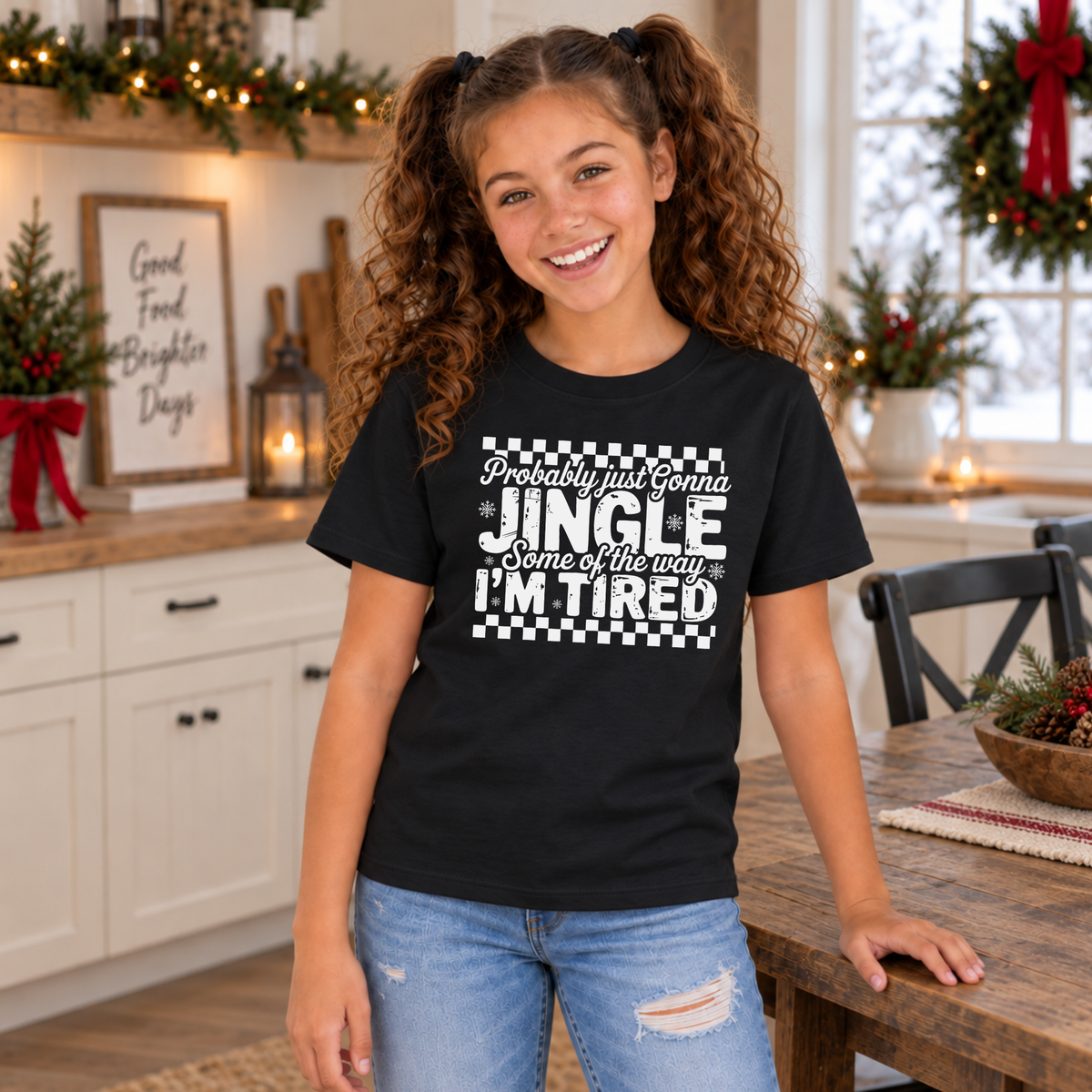 Girl wearing a black youth T-shirt with white Probably Just Gonna Jingle Some of the Way I'm Tired Christmas design in a holiday kitchen