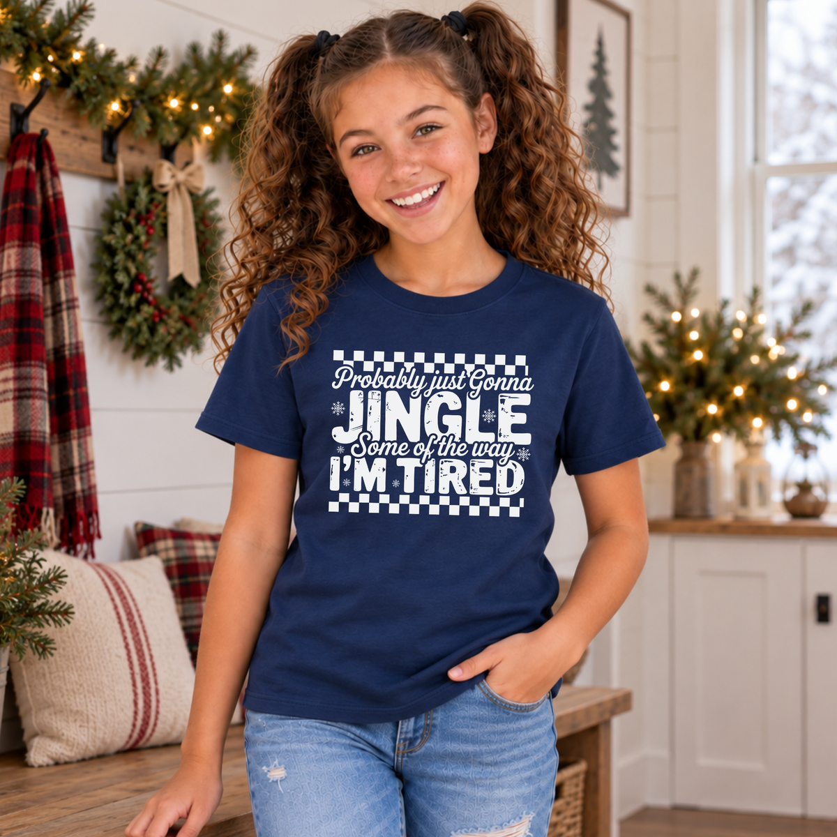 Girl wearing a navy youth T-shirt with white Probably Just Gonna Jingle Some of the Way I'm Tired Christmas design in a festive room