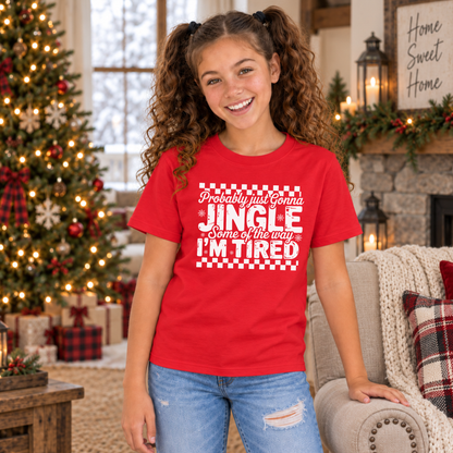 Girl wearing a red youth T-shirt with white Probably Just Gonna Jingle Some of the Way I'm Tired Christmas design by a Christmas tree