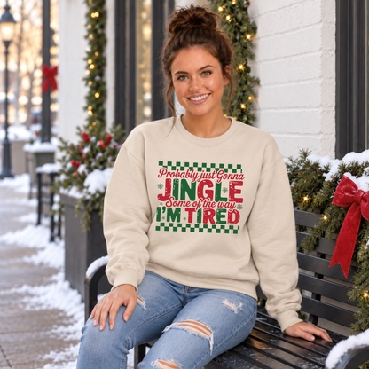 Woman wearing a sand sweatshirt with red and green Probably Just Gonna Jingle Some of the Way I'm Tired Christmas design on a snowy bench