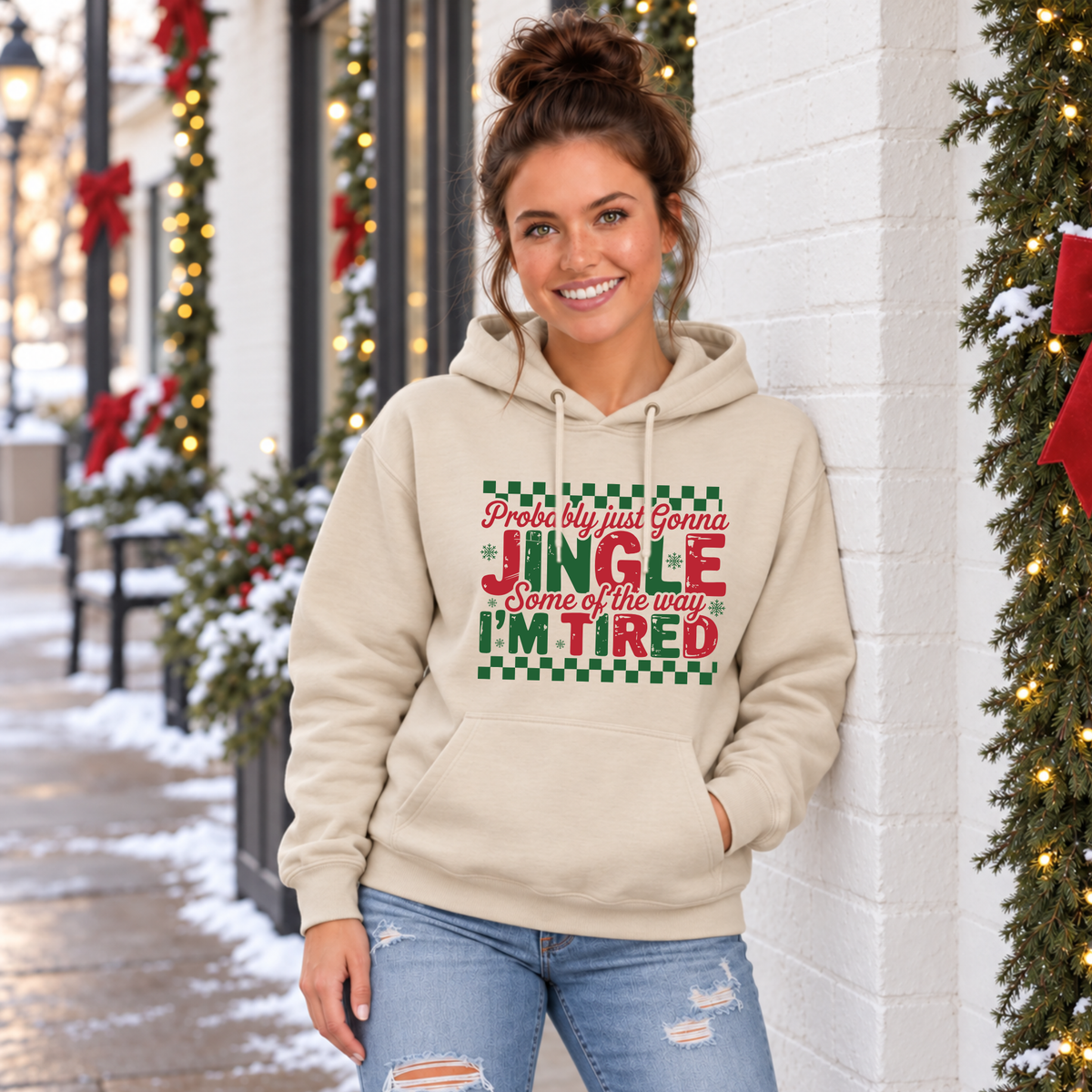 Woman wearing a sand hoodie with red and green Probably Just Gonna Jingle Some of the Way I'm Tired Christmas design outdoors