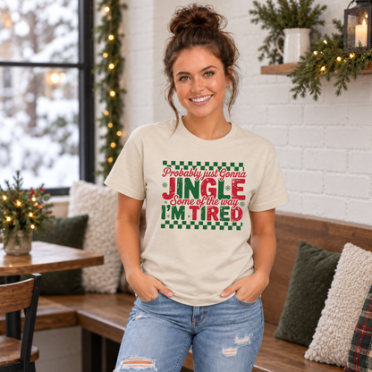 Woman wearing a sand T-shirt with red and green Probably Just Gonna Jingle Some of the Way I'm Tired Christmas design indoors