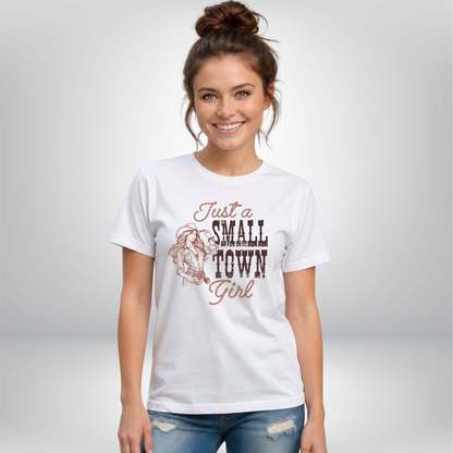 Woman wearing a white T-shirt with the “Just a Small Town Girl” cowgirl graphic, shown in a simple studio-style setting with a light background.