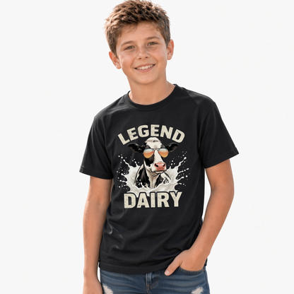 A smiling boy wears a black T-shirt with a “LEGEND DAIRY” graphic showing a black-and-white cow in sunglasses splashing through milk, against a white background.