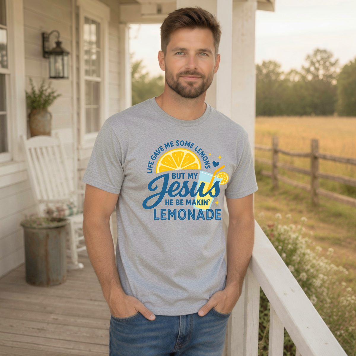 Man modeling a sports gray T-shirt featuring the Jesus Be Makin’ Lemonade faith graphic with lemons, blue script and yellow accents outdoors.