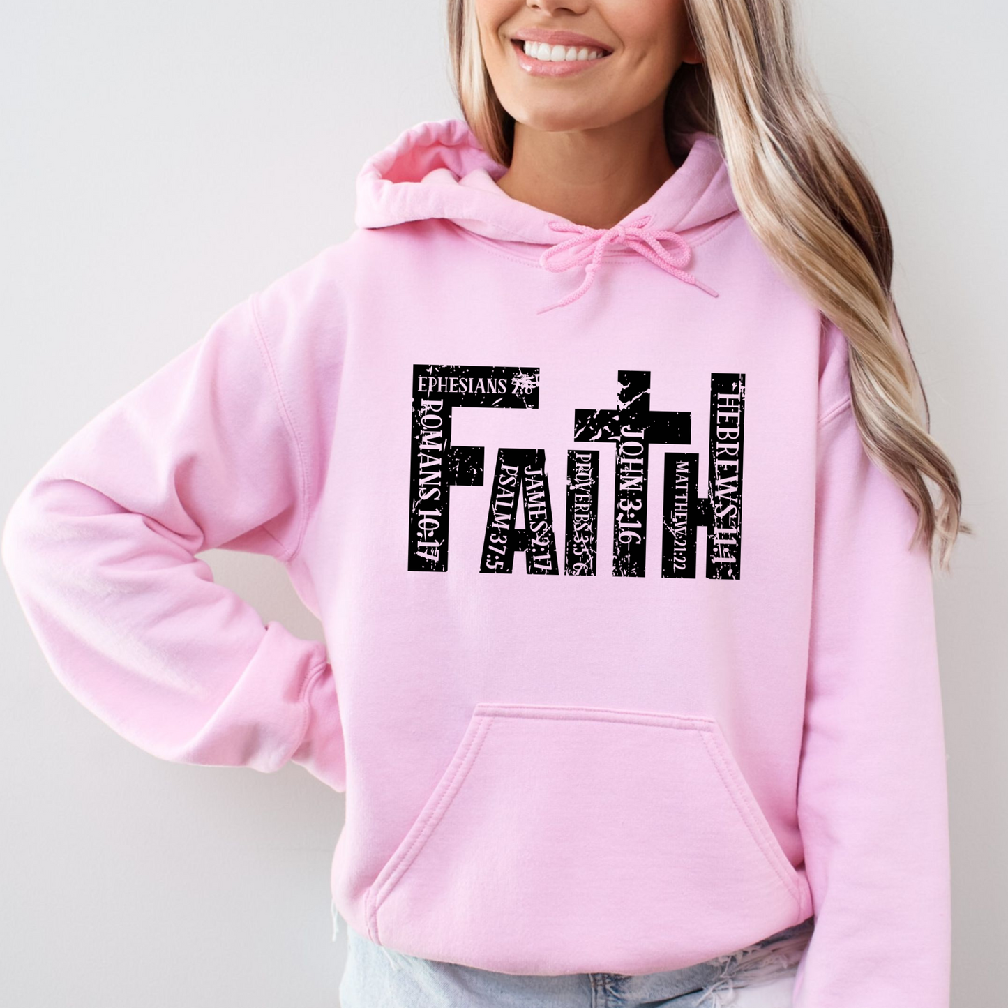 Light Pink Christian hoodie featuring 'FAITH' in bold distressed white letters, designed with Bible verse references including John 3:16, Romans 10:17, Hebrews 11:1, and more. Inspirational religious sweatshirt for faith-based fashion.