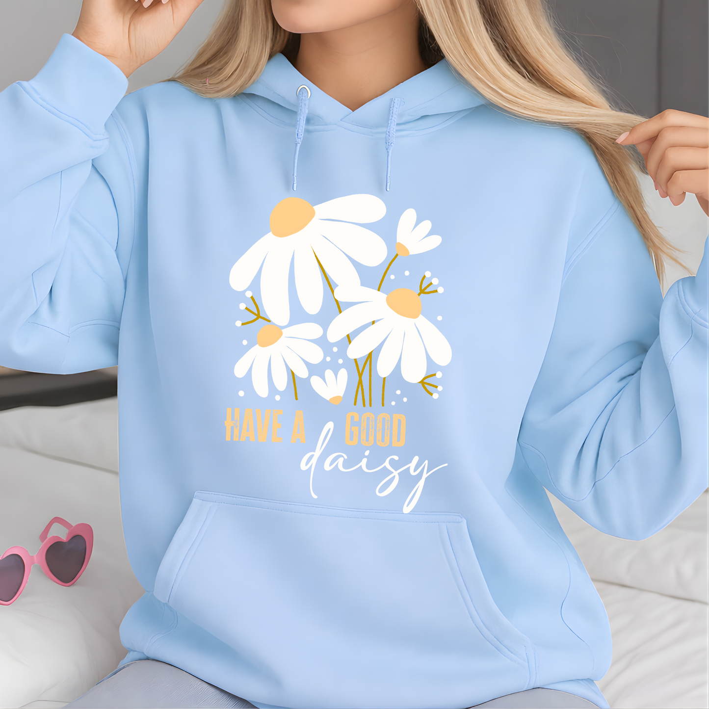 Light blue hoodie with floral design and text 'Have a good daisy' worn by a person.