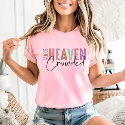 Woman in light pink Make Heaven Crowded T-shirt smiling indoors with casual shorts