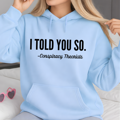 Light blue hoodie with text 'I Told You So. - Conspiracy Theorists' worn by a woman.