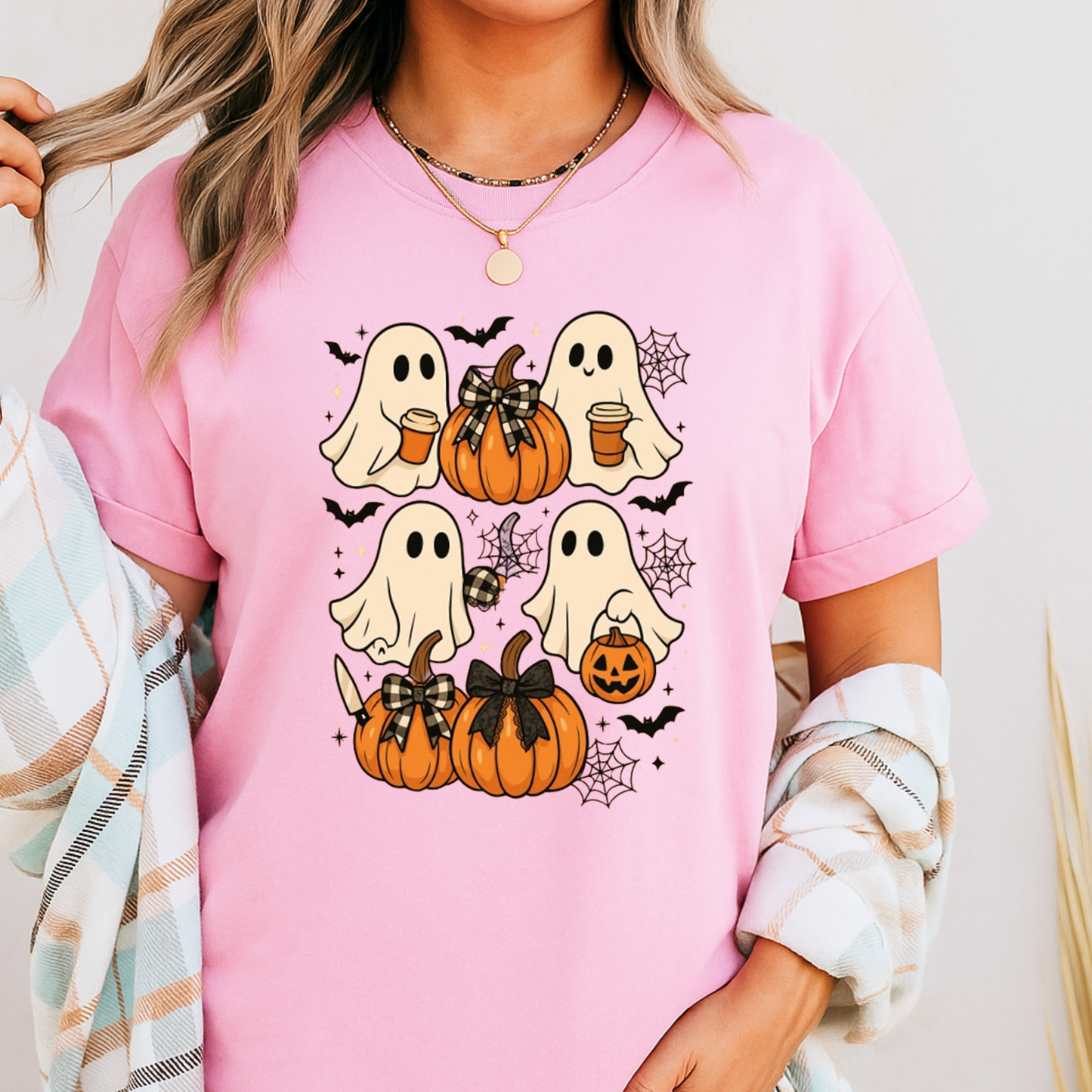Light pink Halloween T-shirt featuring adorable ghosts with pumpkins, bats, and cobwebs. A feminine and fun fall graphic tee perfect for spooky season and casual wear