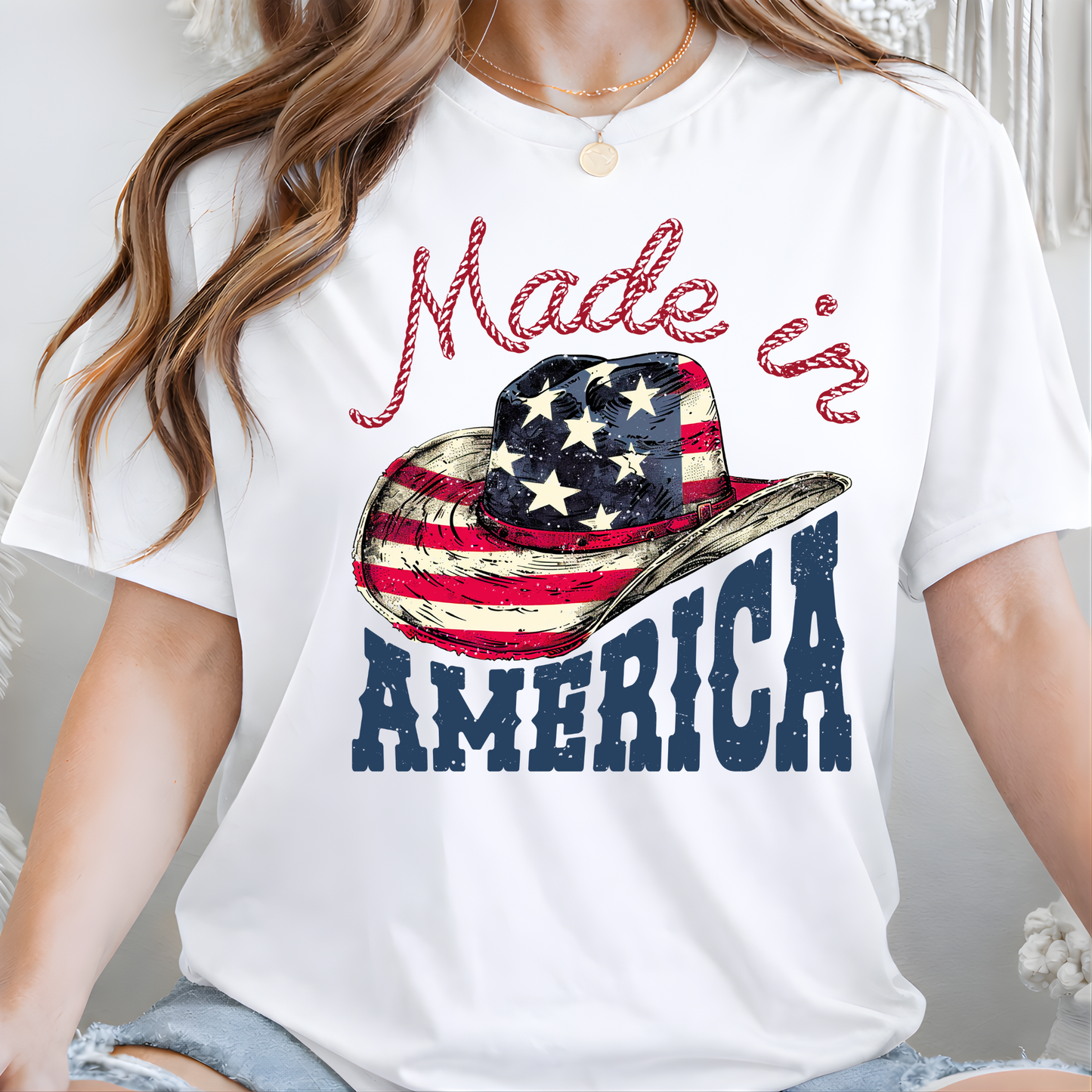White t-shirt with a graphic of a cowboy hat and 'Made in America' text, worn by a person.