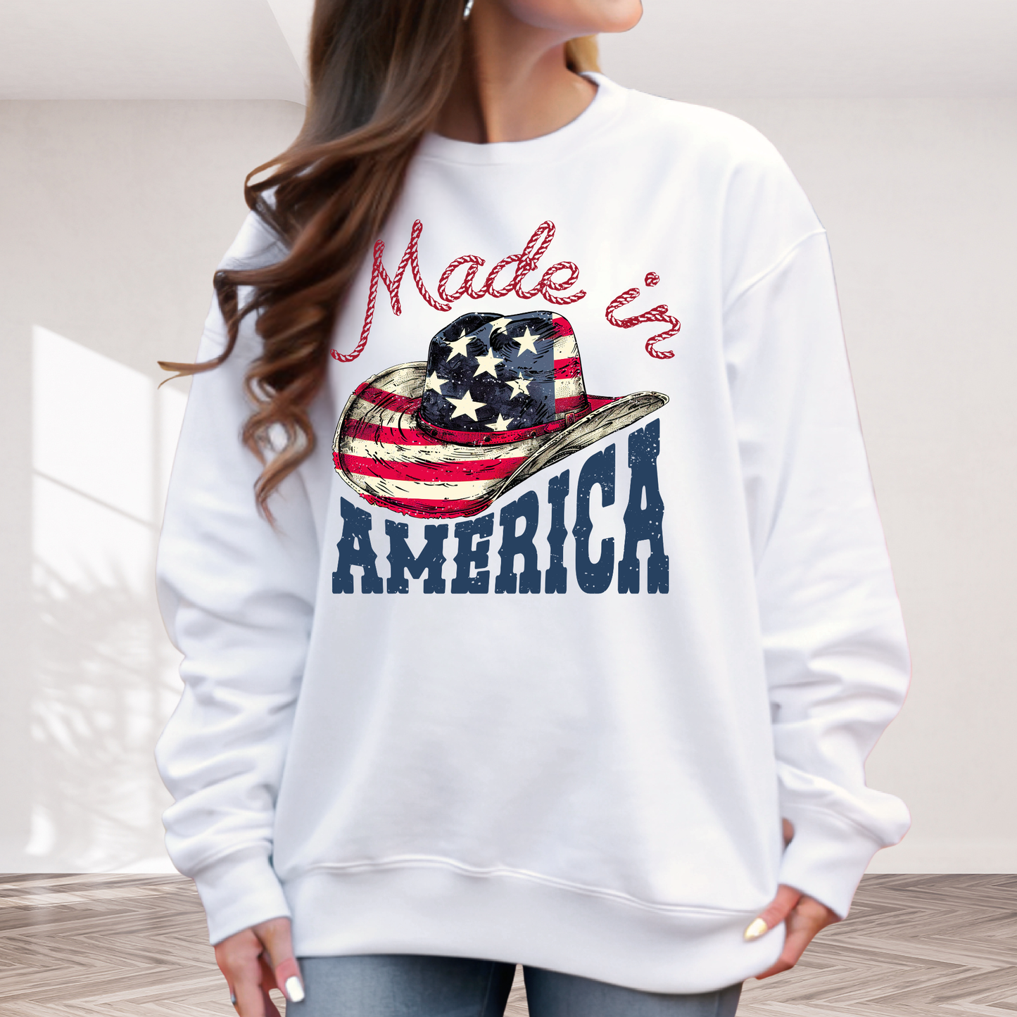 White sweatshirt with 'Made in America' and a cowboy hat graphic, worn by a person.