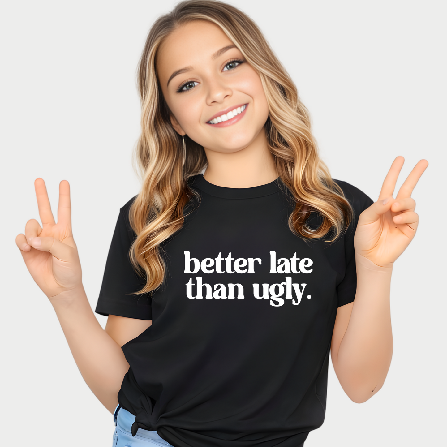 Smiling girl wearing black Better Late Than Ugly youth t-shirt giving peace sign