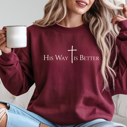 Woman wearing maroon “His Way Is Better” cross sweatshirt holding mug
