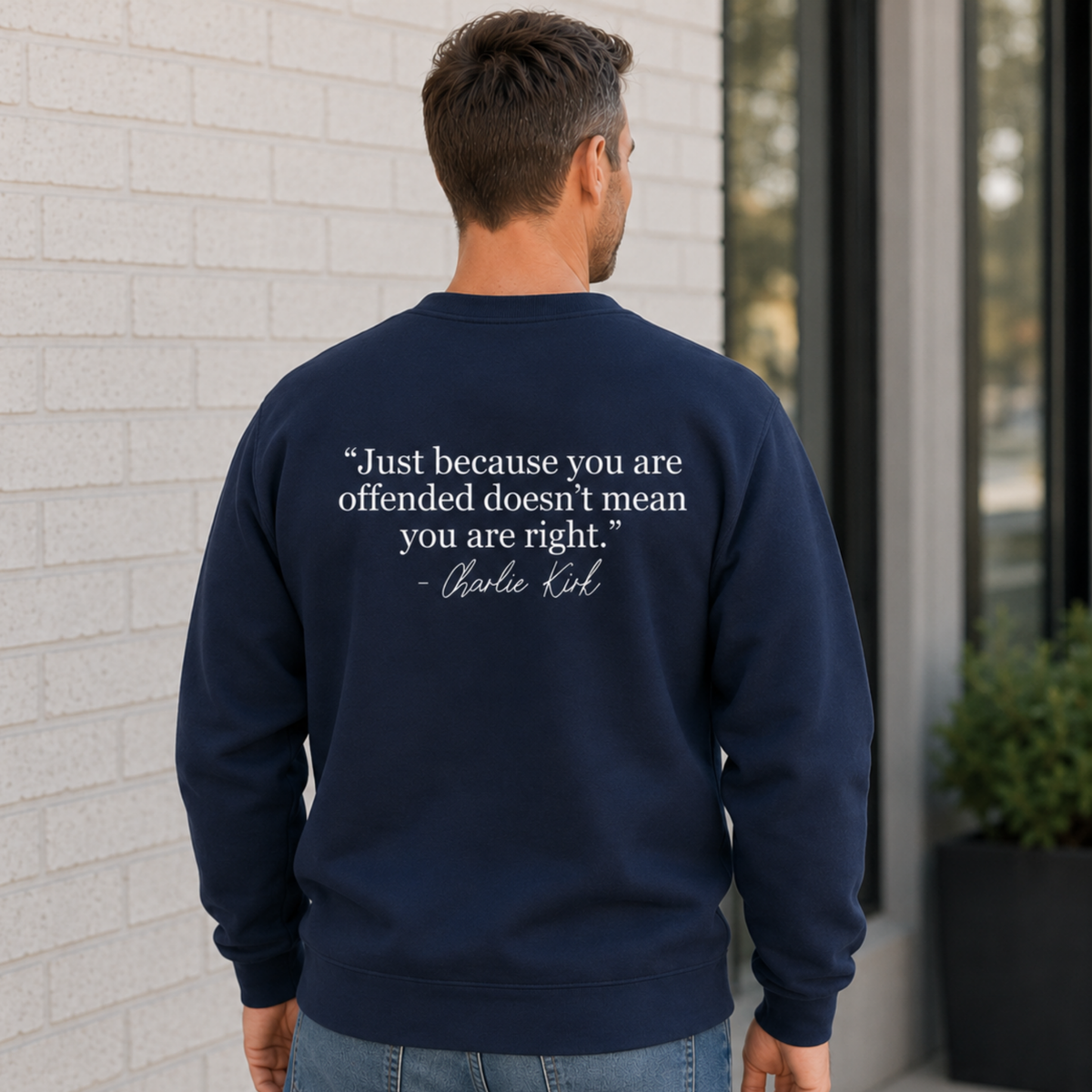 Back view of a man wearing a navy crewneck sweatshirt with a white quote graphic.