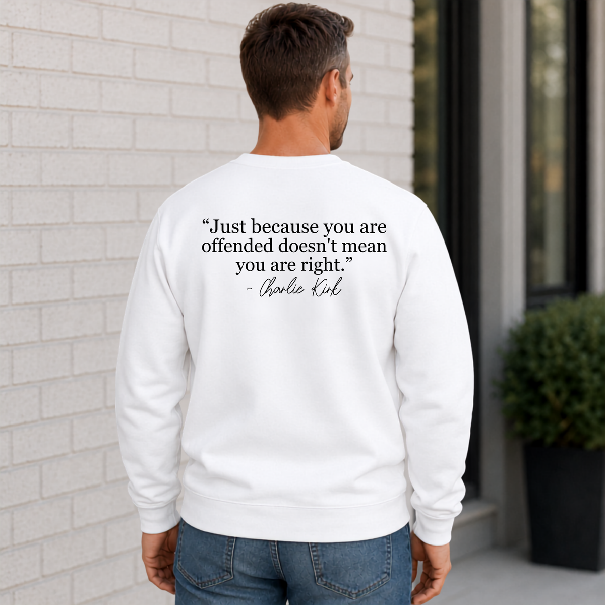 Back view of a man wearing a white crewneck sweatshirt with a black quote graphic.