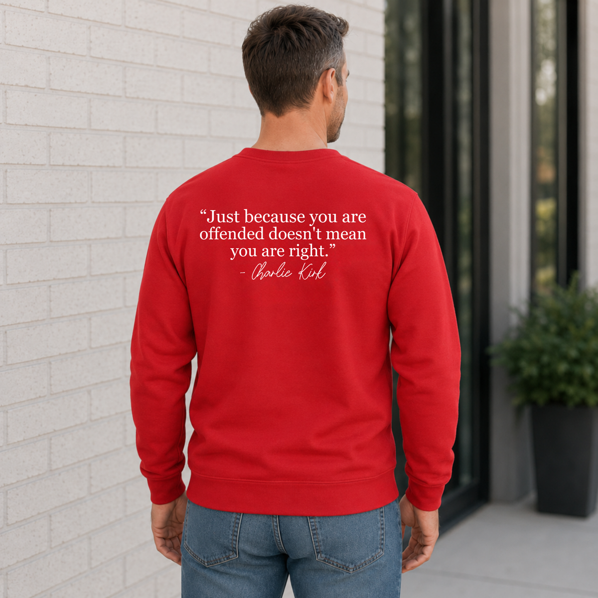 Back view of a man wearing a red crewneck sweatshirt with a white quote graphic.
