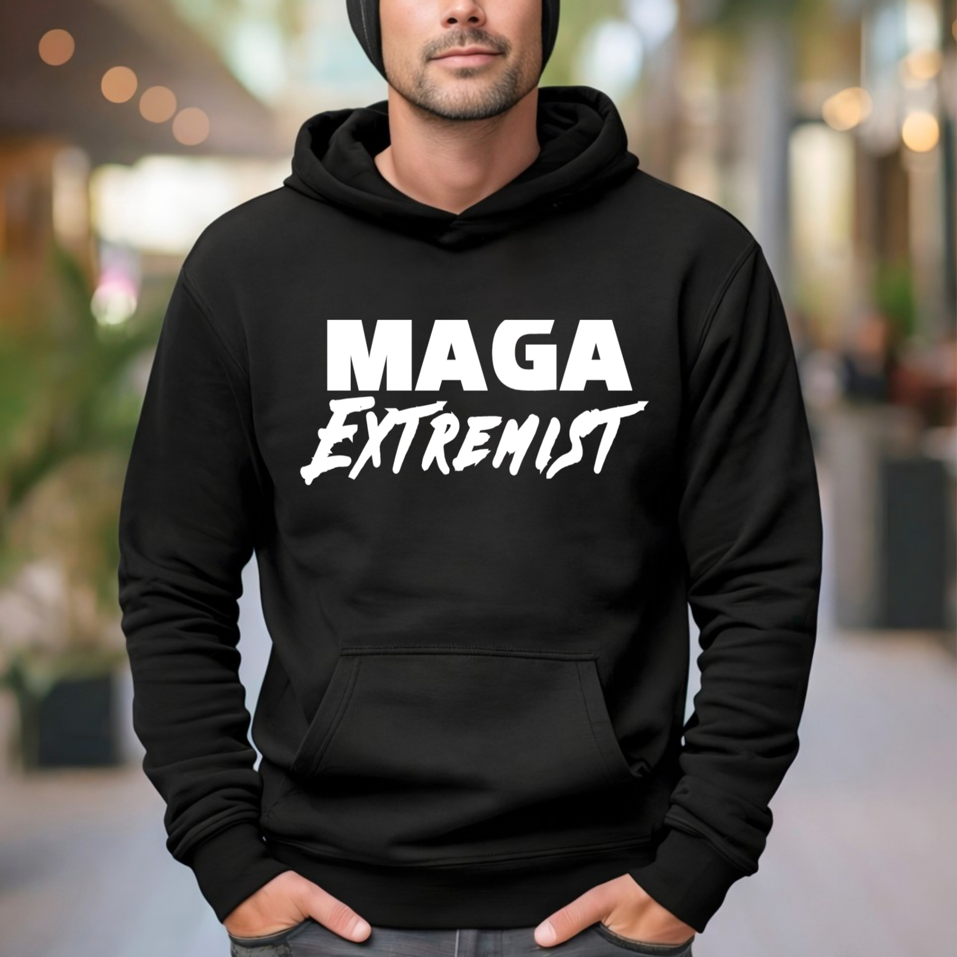Person wearing a black hoodie with 'MAGA Extremist' text in a blurred outdoor setting