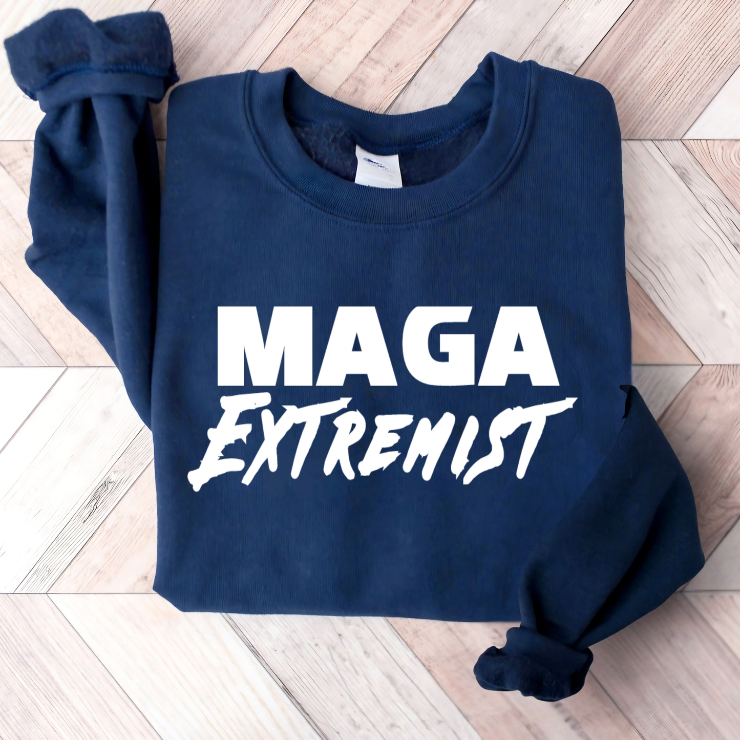 Navy blue sweatshirt with 'MAGA Extremist' text on a wooden floor.