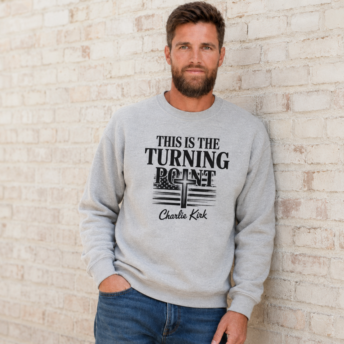 Man wearing a sports gray crewneck sweatshirt with black This Is the Turning Point cross graphic.