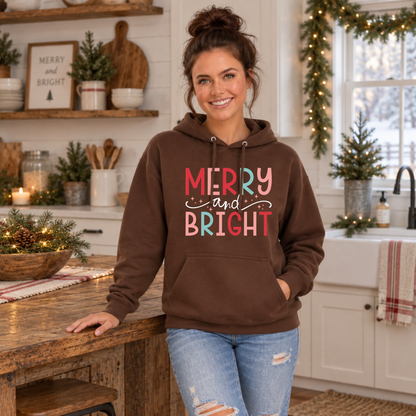 Woman wearing a brown hoodie with colorful Merry and Bright Christmas design in a rustic holiday kitchen