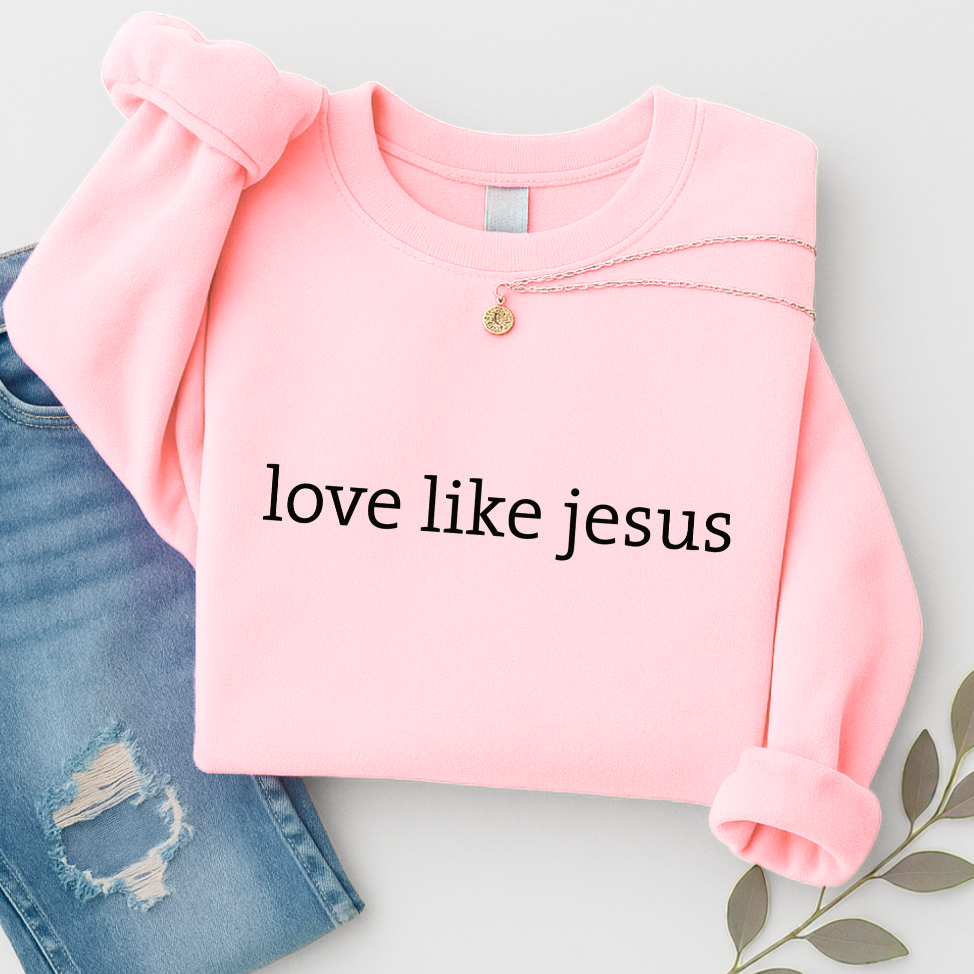 Pink sweatshirt with 'love like jesus' text on a light gray background
