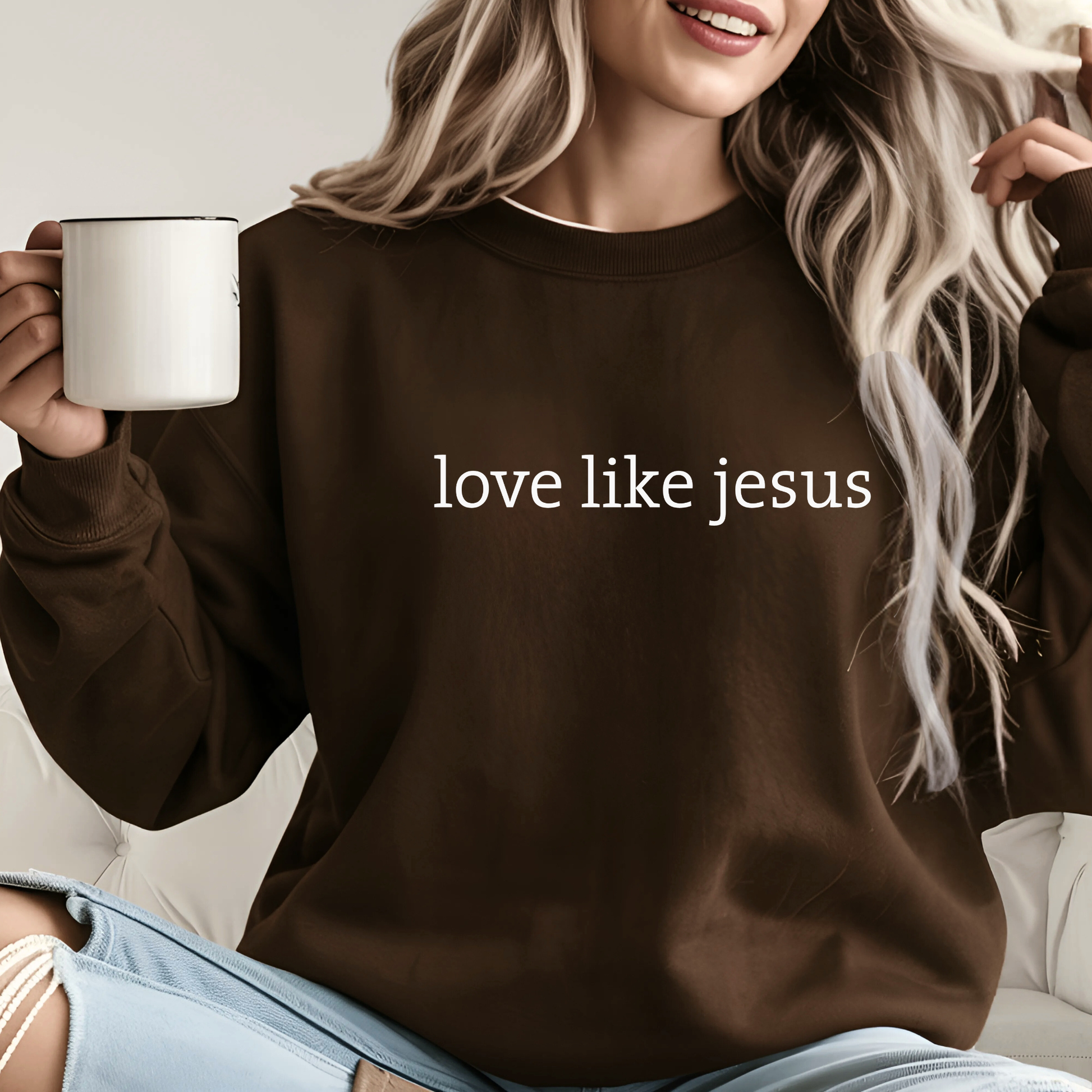 Woman in dark brown “Love Like Jesus” sweatshirt holding a mug