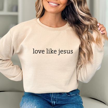 Woman wearing sand “Love Like Jesus” sweatshirt smiling indoors