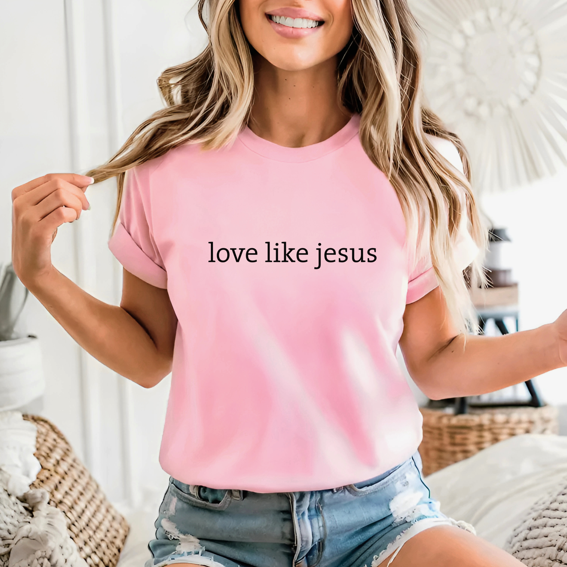 Woman in light pink “Love Like Jesus” shirt, feminine and casual outfit