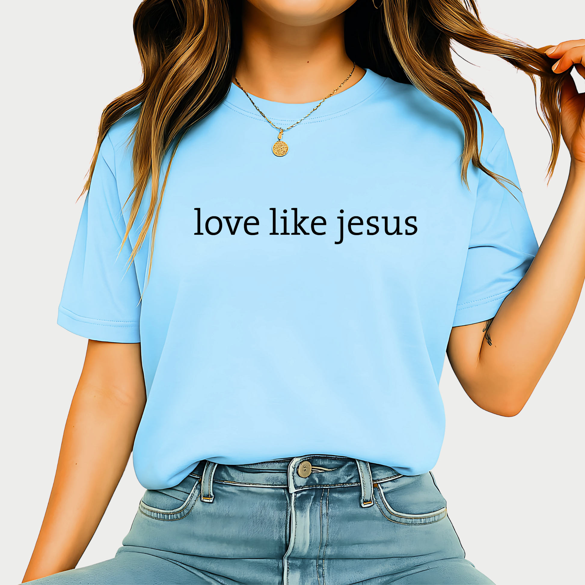 Woman wearing light blue “Love Like Jesus” T-shirt styled with denim jeans