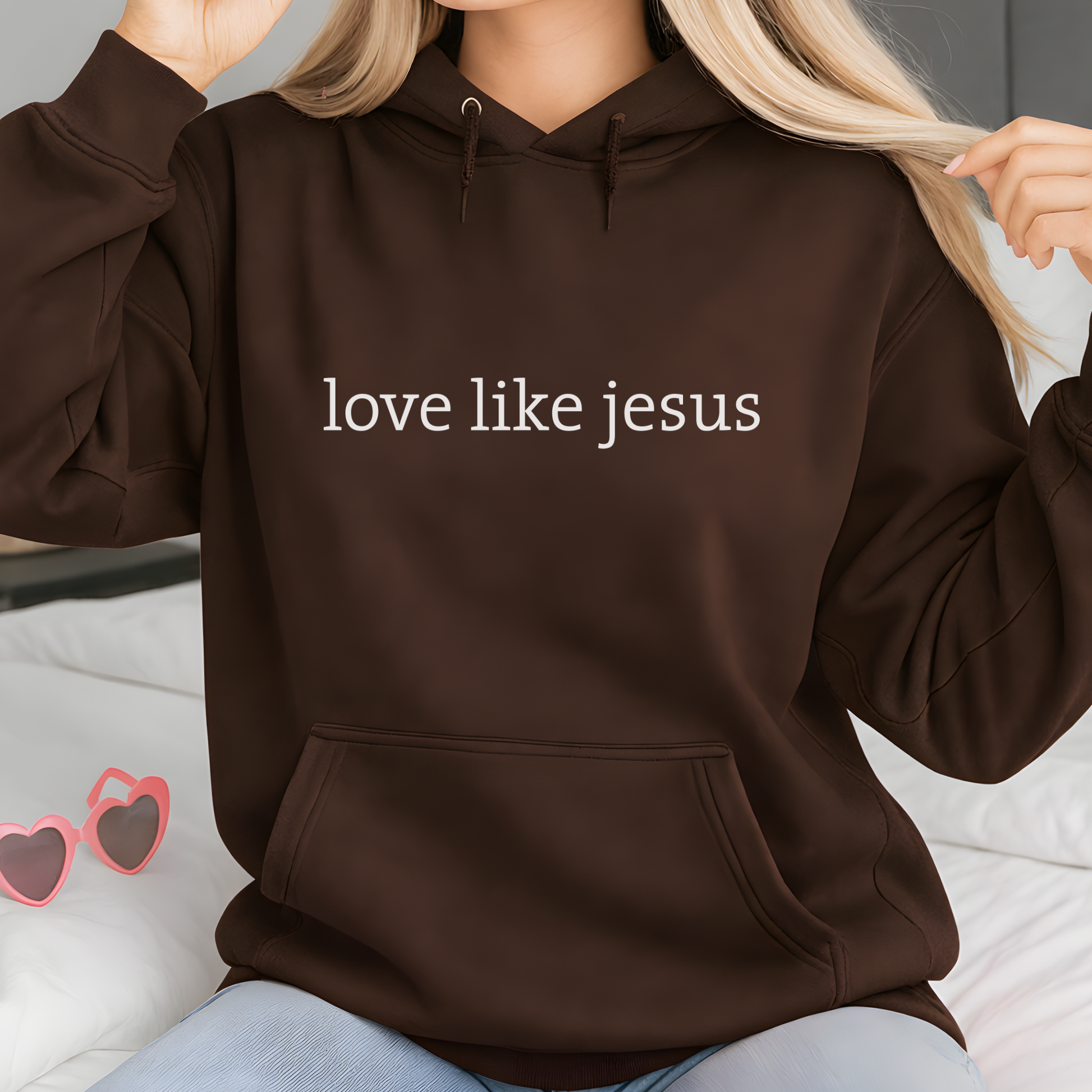 Lifestyle image of woman wearing brown hoodie with “love like jesus” text design