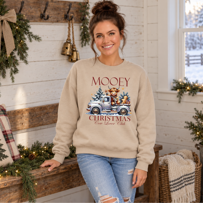 Woman wearing a sand Mooey Christmas cow graphic sweatshirt in a cozy holiday room.