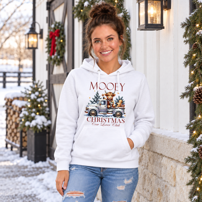 Woman wearing a white Mooey Christmas cow graphic hoodie outside a snowy holiday storefront.