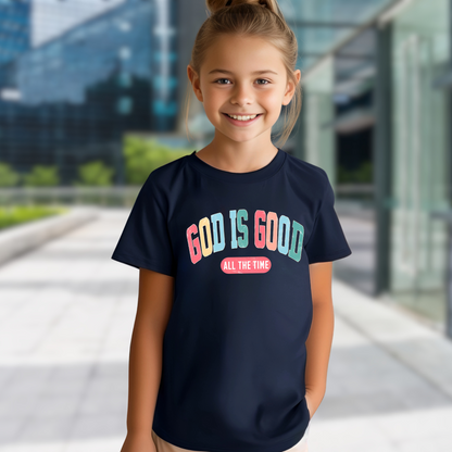 Smiling girl wearing a navy T-shirt with the message 'God Is Good All the Time' in colorful text, symbolizing faith and positivity. Perfect for Easter and Christian-themed apparel.