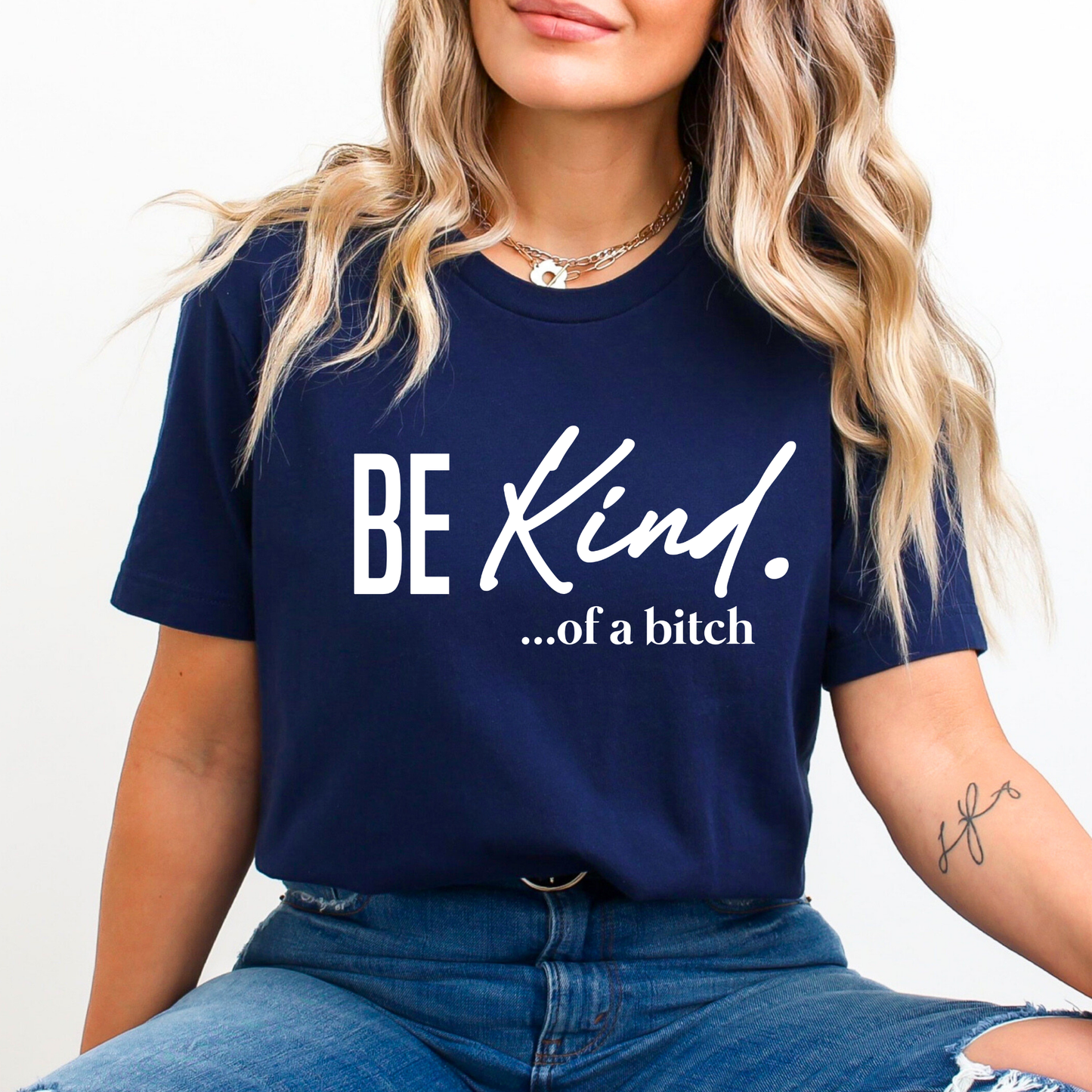Navy shirt with white “Be Kind…of a bitch” print worn by a smiling woman