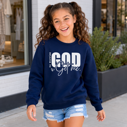 Youth model wearing a navy No Worries God Got Me crewneck sweatshirt with bold white lettering outside a storefront.