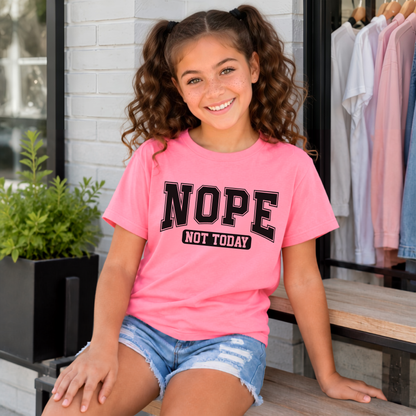 Bright Pink NOPE NOT TODAY youth T-shirt with black block lettering, modeled while seated on a boutique bench.