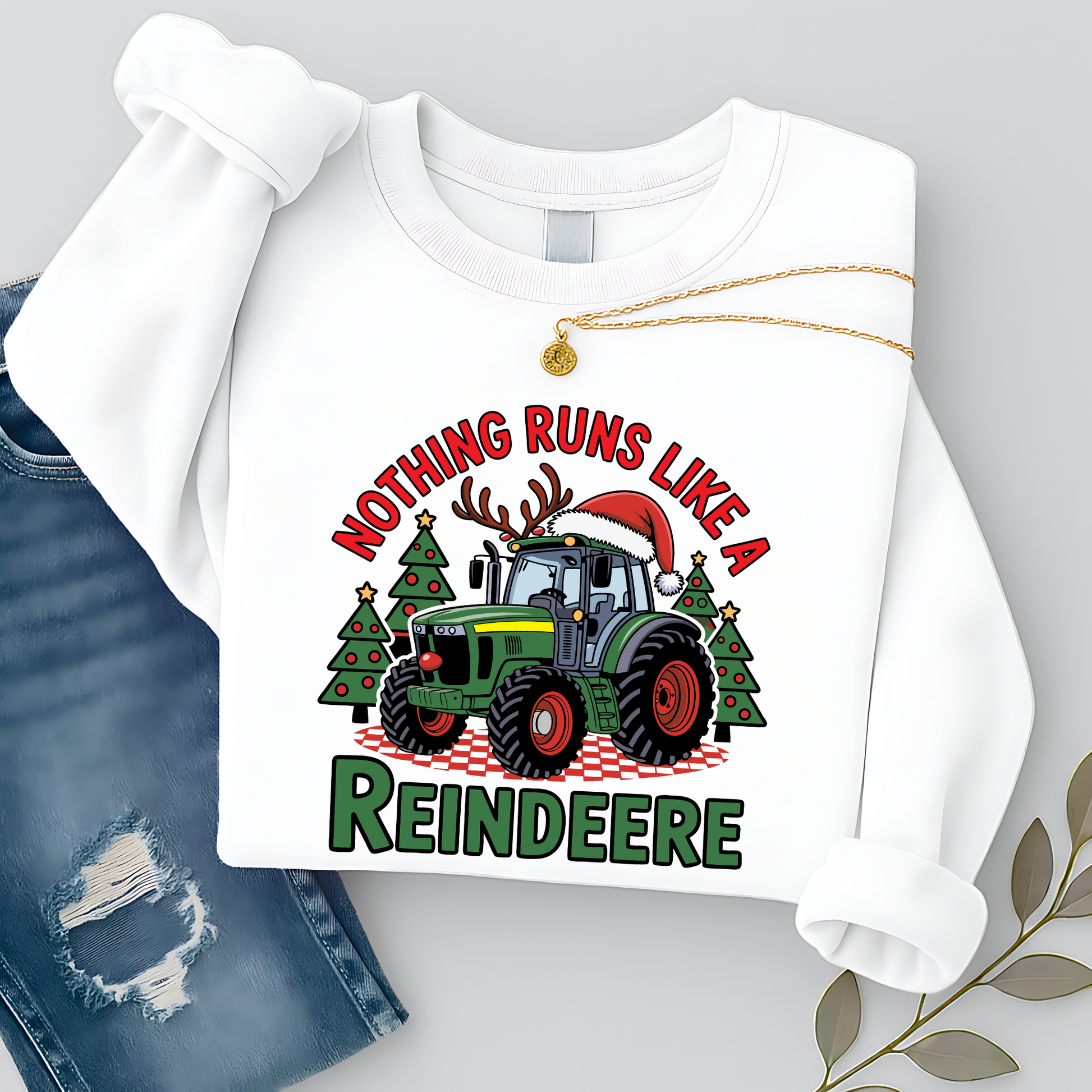 White Christmas tractor sweatshirt for women, flat lay with necklace and jeans, showcasing festive tractor holiday design. Great country Christmas pullover gift idea.