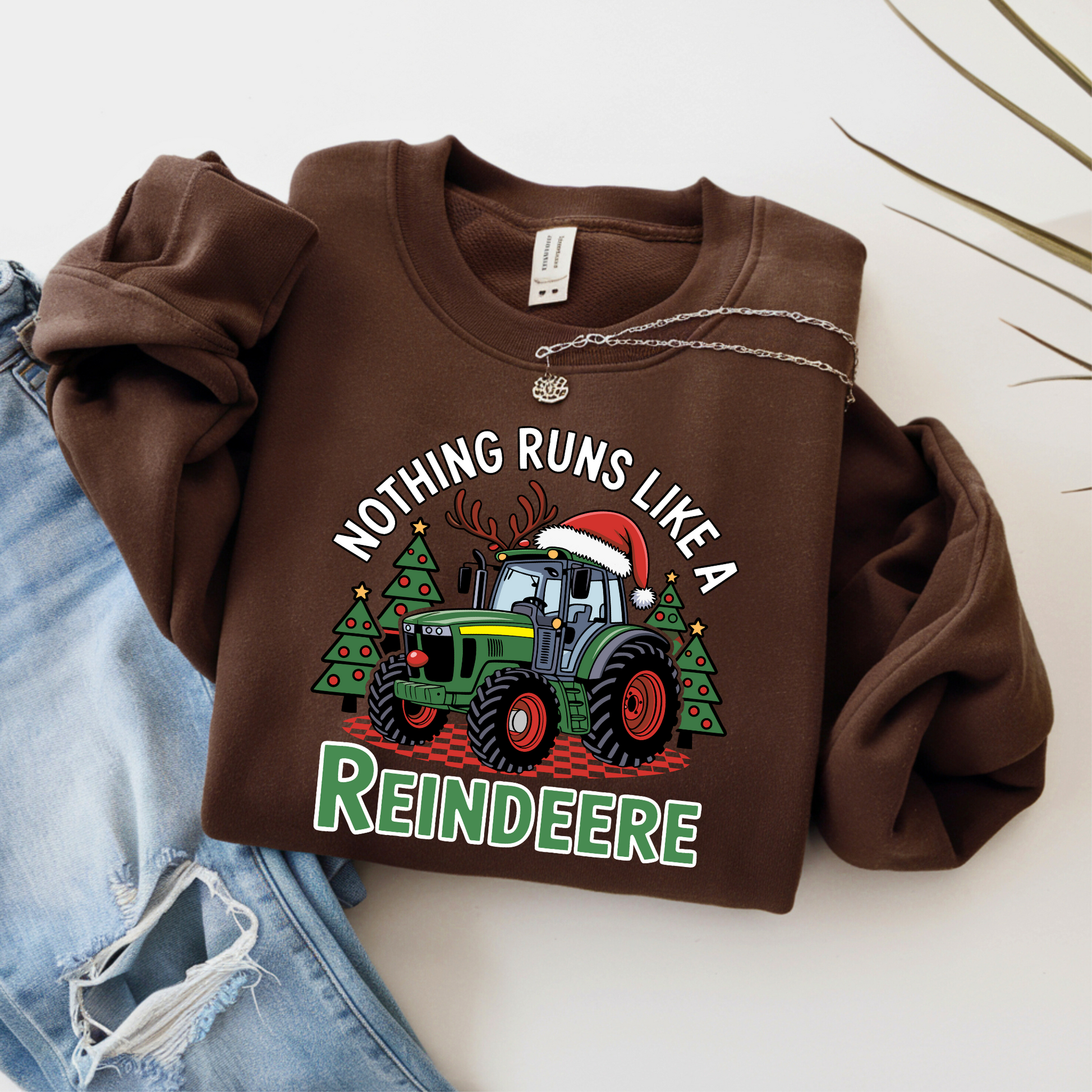 Brown Christmas tractor sweatshirt for women, styled flat with jeans and necklace, featuring funny farm tractor holiday design.