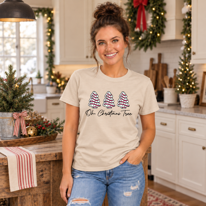 Woman in a sand Oh Christmas Tree T-shirt in a holiday kitchen beside a rustic wooden island.