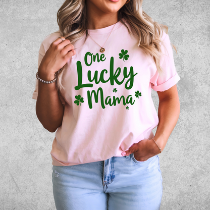 A stylish pink t-shirt with "One Lucky Mama" in green script, decorated with shamrocks. Perfect for moms celebrating St. Patrick’s Day in a cute and festive way.